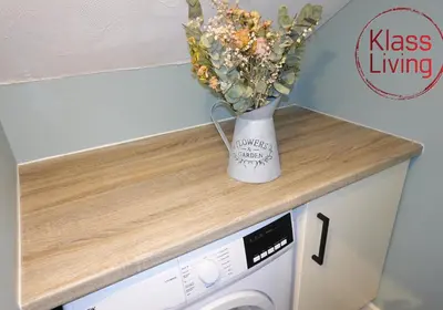 a vase of flowers sitting on top of a washing machine at Mossend Apartment by Klass Living Bellshill in Mossend