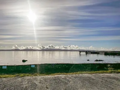 a body of water with a pier and a bird in the water at Burnside Cottage in Bruichladdich