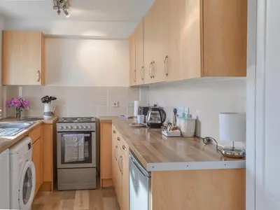 a kitchen with wooden cabinets and a stove top oven at Burnside Cottage in Bruichladdich