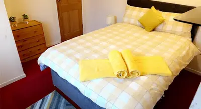 a bedroom with a bed with yellow towels on it at Wallace View - Holiday Home in Stirling