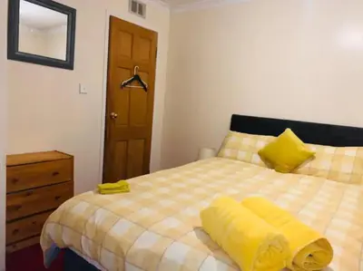 a bedroom with a bed with a yellow blanket on it at Wallace View - Holiday Home in Stirling