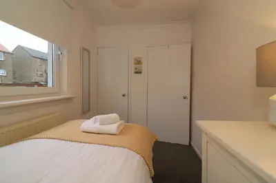a white bedroom with a bed and a window at Signature - North View in Cambusnethan