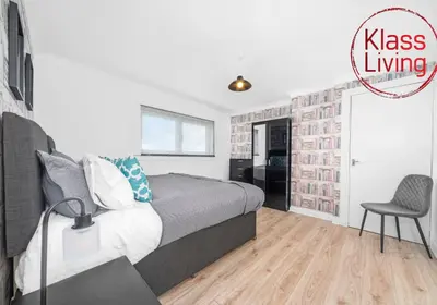 a bedroom with a bed and a chair in it at Berwick Apartment by Klass Living Coatbridge in Coatbridge