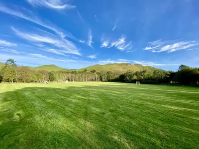 a large green field with mountains in the background at Balbeg Cottage in Straiton
