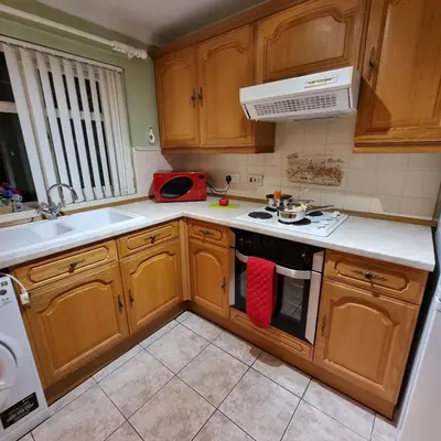 a kitchen with wooden cabinets and a stove top oven at PREMIER - Whifflet Apartment in Coatbridge