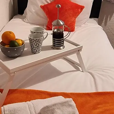 a tray with two cups and a bowl of fruit on a bed at PREMIER - Whifflet Apartment in Coatbridge