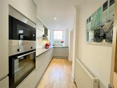 a kitchen with white cabinets and a black appliance at Elite 3 Bed New Town Apt with Private Walled Garden in Edinburgh
