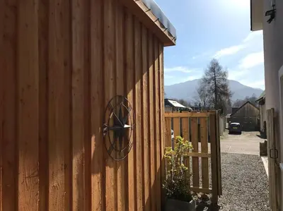 a clock on the side of a wooden fence at The Den - your cosy sleepover space in Saint Fillans