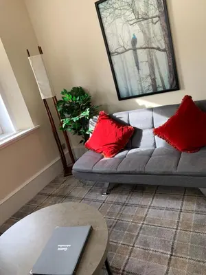 a living room with a couch with red pillows and a table at clyde hub in Gourock