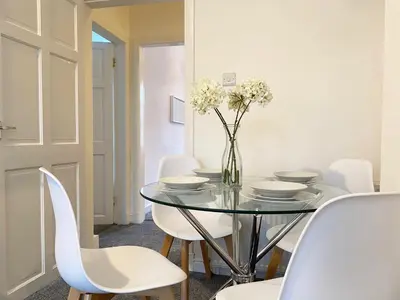 a dining room with a glass table and white chairs at Gladsmuir House in Glasgow