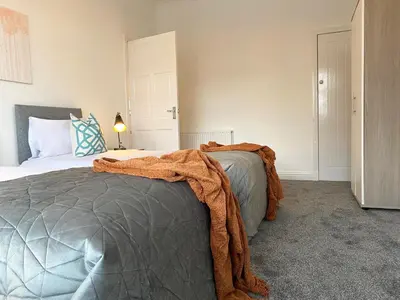 a bedroom with a bed with an orange blanket on it at Gladsmuir House in Glasgow
