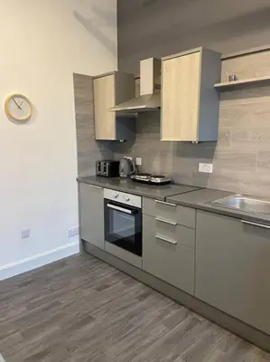 a kitchen with stainless steel appliances and wooden cabinets at Newly refurbished town centre apartment in Oban
