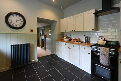 a kitchen with white cabinets and a clock on the wall at Stormont House in Keilour