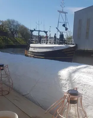 a boat is going down a river at Stunning Riverside Town House with views Ayrshire in Girvan