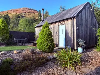 a wooden shed with a door in a garden at The Bothy - your unique luxury refuge in Saint Fillans