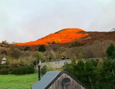 a hill with an orange mountain in the background at The Bothy - your unique luxury refuge in Saint Fillans