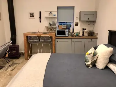a bedroom with a bed and a kitchen with a stove at The Bothy - your unique luxury refuge in Saint Fillans