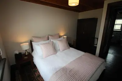 a bedroom with a bed with white sheets and pink pillows at Easdale Cottage in Ellanbeich