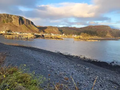 a beach with a pier in the middle of the water at Easdale Cottage in Ellanbeich