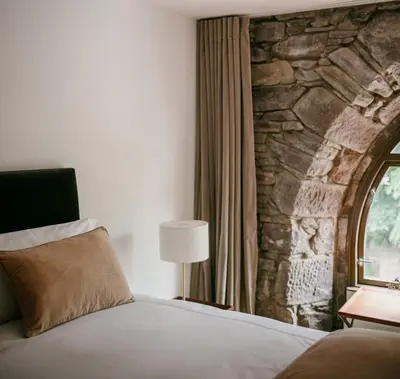 a bedroom with a bed and a stone wall at The Church Tower in Crieff