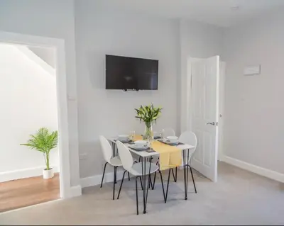a white dining room with a table and chairs at The Mila - Ayr Racecourse - Coorie Doon Stays in Ayr