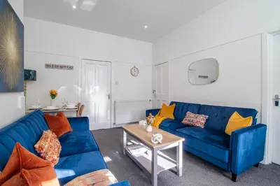 a living room with a blue couch and a table at Bella House - 3 bed house in Glasgow in Glasgow