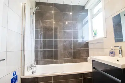 a bathroom with a shower and a tub and a sink at Bella House - 3 bed house in Glasgow in Glasgow