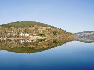 a reflection of a house on a lake at The Quaich in Stron-fearnan