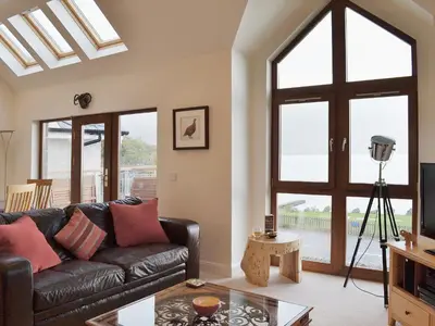 a living room with a leather couch and a window at The Quaich in Stron-fearnan