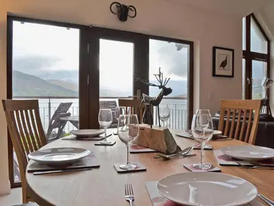 a dining room table with glasses and a view of the ocean at The Quaich in Stron-fearnan