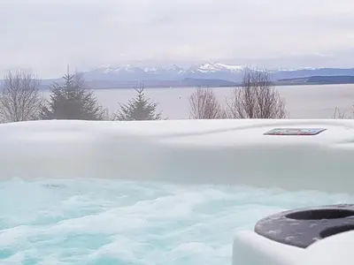a hot tub covered in snow with mountains in the background at Knock Old Castle in Largs