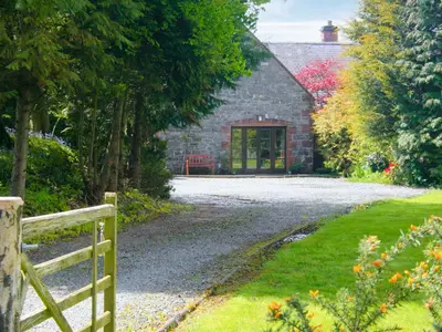 a stone house with a fence and a gravel driveway at The Coach House - Uk38000 in Kirkcowan