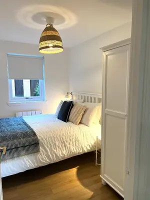 a bedroom with a white bed and a window at Bellevue Apartment in Largs