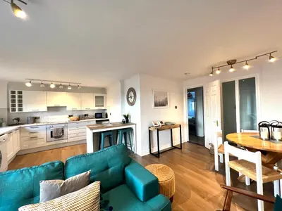a living room with a blue couch and a table at Bellevue Apartment in Largs