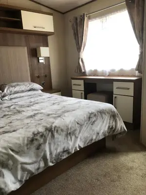 a bedroom with a bed and a desk and a window at River View 46 in Dunoon