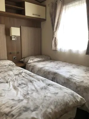two beds in a room with a window at River View 46 in Dunoon