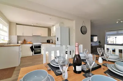 a dining room table with a bottle of wine on it at Signature - Honeywell House in Chapelhall
