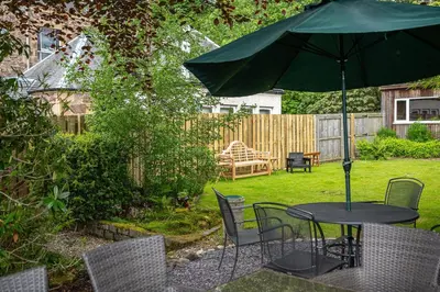 a table and chairs with an umbrella in a yard at Annfield House, Callander in Callander