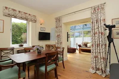 a living room with a table and chairs and a television at The Neuk in Tighnabruaich
