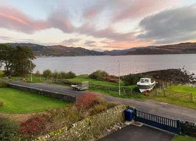 a boat is parked on the side of a lake at The Neuk in Tighnabruaich