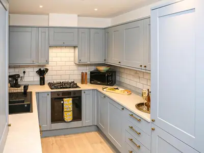 a kitchen with gray cabinets and a stove top oven at Forget Me Not Cottage in Culross
