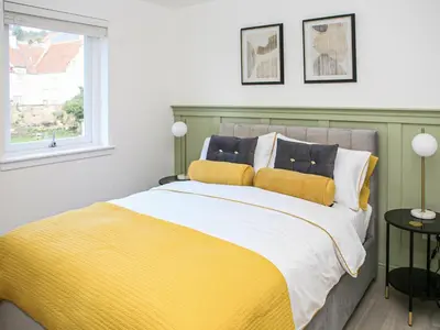 a yellow and white bed in a room with a window at Forget Me Not Cottage in Culross