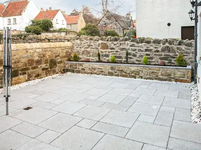 a stone retaining wall and a stone patio at Forget Me Not Cottage in Culross