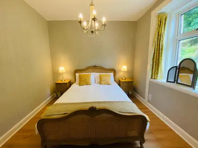 a bedroom with a bed with two lamps and a chandelier at Upper Villa, Tighnabruiach, Argyll & Bute in Tighnabruaich