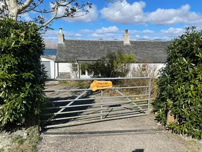 a gate with a sign on it in front of a house at The Old Ferryhouse in Port Appin