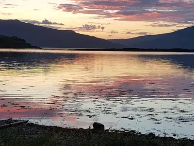 a sunset over a body of water with mountains at The Old Ferryhouse in Port Appin