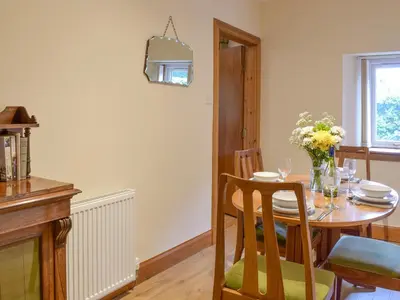 a dining room table with a vase of flowers on it at The Lodge in Linlithgow