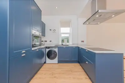 a kitchen with blue cabinets and a washing machine at 5 Bed cottage with Hot tub in Bannockburn