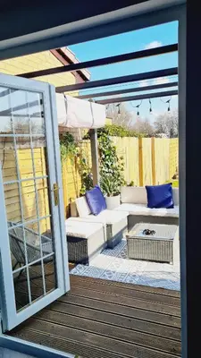 a patio with a couch and an open door at Beautiful 2bed house with garden, walking distance to town - FREE parking in Glasgow