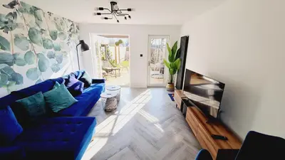 a living room with a blue couch and a flat screen tv at Beautiful 2bed house with garden, walking distance to town - FREE parking in Glasgow